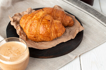 Tasty croissant with cup of coffee with milk on kitchen table
