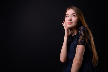 Fototapeta premium Young beautiful woman with long brown hair against black background