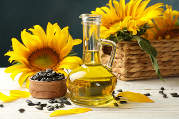 Composition with sunflower, seeds and oil on white wooden background