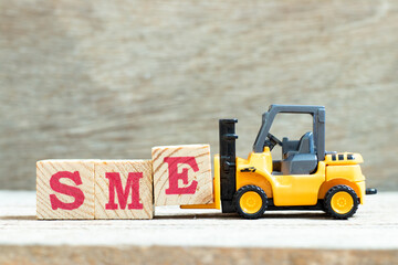Toy forklift hold letter block e to complete word SME (abbreviation of Small and medium sized...