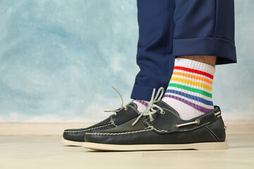 Man in blue pant, loafers and LGBT socks against blue background