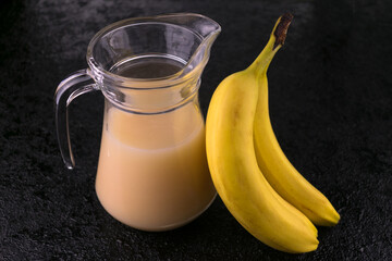 A jug of banana juice on a black background. Close-up.