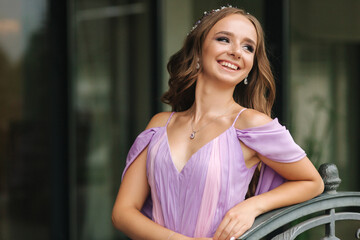 Portrait of beautiful young woman stand on terrace in lavender evening dress. Elegant makeup