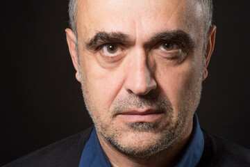 Ritratto stretto di un uomo che guarda con espressione dura e severa isolato nell'oscurità