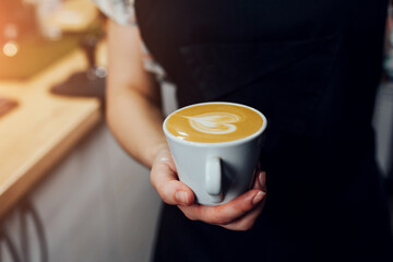 Milk foam from a cappuccinator to create an art pattern on the top of the coffee - a professional work of a barista