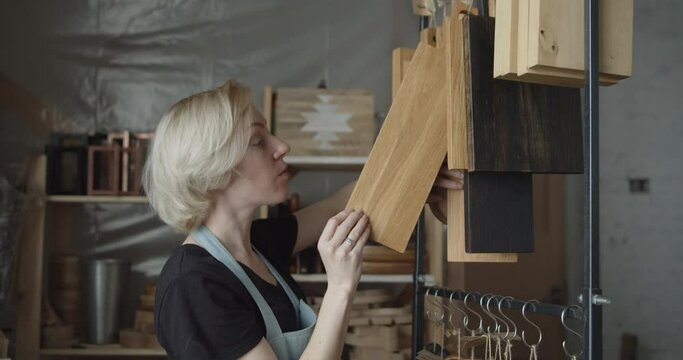 Young woman carpenter chooses wooden cutting board