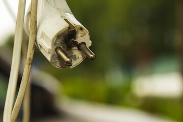 The white plug burned after a short circuit, the background is blurred.