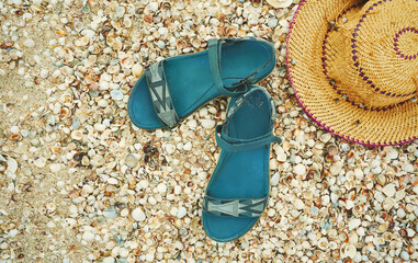 Straw hat and sandal on beach. Top view summer accessories on seashells texture. Tropical summer...