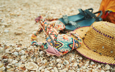 Close-up woman vacation set, beach accessories on seashells. Summer concept of beach, straw hat,...