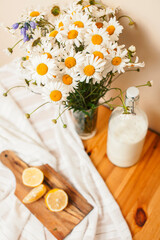 Obraz na płótnie Canvas Simply stylish wooden kitchen with bottle of milk and glass on table, summer flowers camomile, healthy foog moring concept