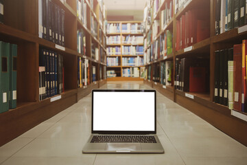 Laptop with blank screen on floor. interior background, bookshelf, library.Educational technology concept.