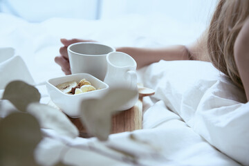 爽やかな朝に寝室のベッドでくつろぐ白いワンピースの女性