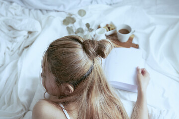 Obraz na płótnie Canvas 爽やかな朝に寝室のベッドでくつろぐ白いワンピースの女性