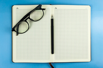 Black-rimmed glasses lie on an open notebook