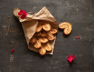 Palmier cookies in a paper bag on a black background. Top view