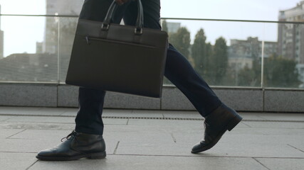 Businessman legs walking on urban street. Male worker taking walk around city