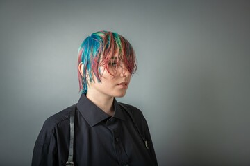 Portrait of a young woman with multi colored hair against a grey background