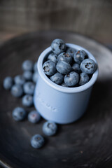dark tones still life with blueberries on grey handmade ceramic plate