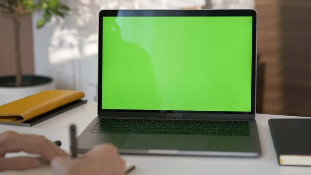 Girl looking at green screen laptop computer in living room watching movie, video content. Indoors. Online education. Business woman or female freelancer working from home office. Closeup 4K