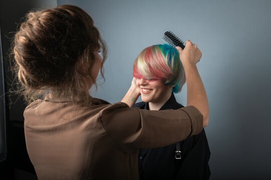 Girl hairdresser styling hair girl with rainbow hair beauty fashion style