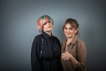 Two pretty young white girls smiling and posing on grey background people portrait with positive emotions