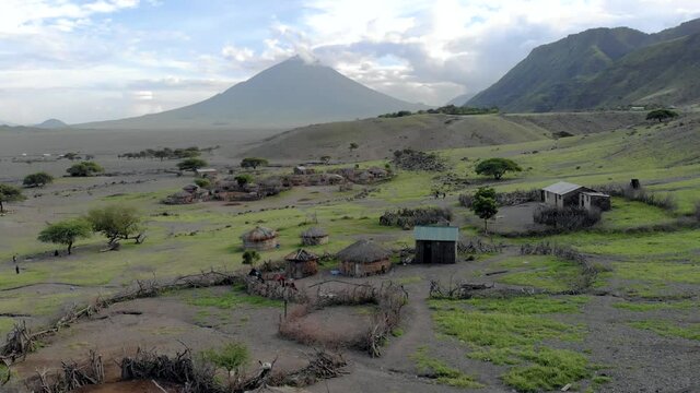 Aerial Flyby View on the Maasai village in front of the Ol Doinyo Lengai, Mountain of God in the Maasai language, Engare Sero village in Arusha Region i the Northern Tanzania, Africa, at Sunset time.