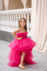 Beautiful little girl in pink fluffy dress give an air kiss