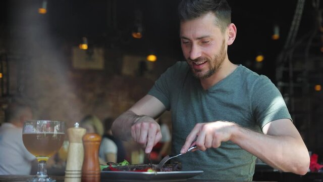 Man Eating Food At Restaurant, Cutting Meat Steak With Knife Sitting At Table At Barbecue Cafe