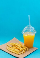American food concept french fries and orange juice on a blue background, delicious fast food. 