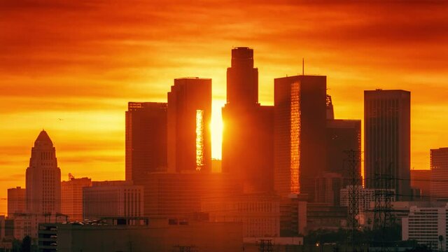 Sunset sun setting behind downtown Los Angeles skyline silhouette. Zoom out landmark city buildings. Timelapse, 4K UHD.
