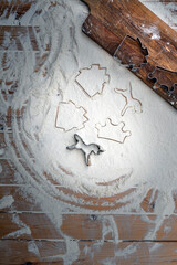 Shaped cookie cutters and white flour on old rustic wooden table, top view.  Copy space for your text.