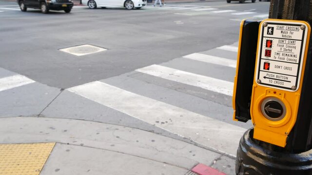 Traffic light button on pedestrian crosswalk, people have to push and wait. Traffic rules and regulations for public safety in USA. Zebra street crossing on road intesection in San Diego, California.