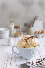Rustic homemade creamy ice cream in ceramic cup on white wooden table