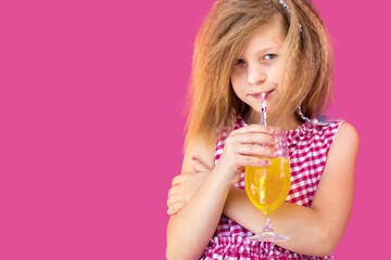 Little blonde girl in red checkered dress drinking juice