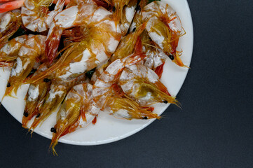 Sweet shrimp in white dish on black background, Flat lay