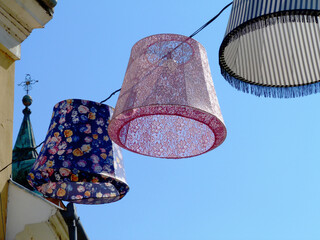 colorful decorative isolated lampions suspended on electrical wire overhead above public street....