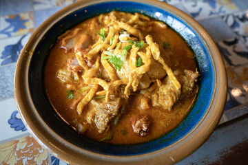 A bowl of spicy curry noodle with chicken and pork meat, Famous menu of Thailand Northern traditional food.