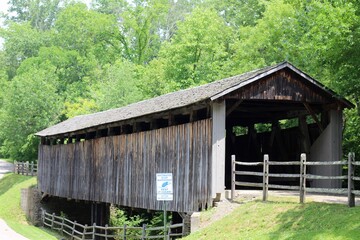 The wood covered bridge in the country on a sunny day.