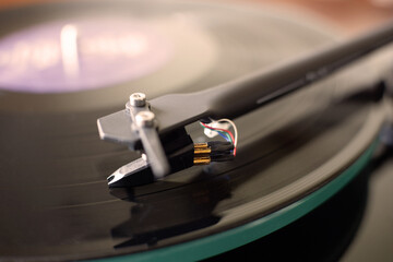Fototapeta na wymiar Black vinyl record player. Closeup image of cartridge and tonearm. The stylus slides on a vinyl disc.
