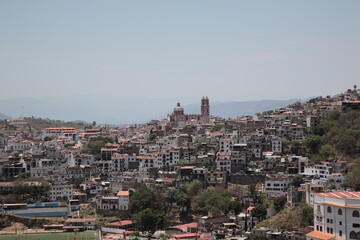 Fototapeta premium View of Santa Prisca Church and dense white houses with tile roofs on the hill in Taxco, Mexico 