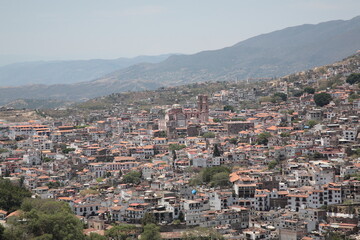 Fototapeta na wymiar View of Santa Prisca Church and dense white houses with tile roofs on the hill in Taxco, Mexico 