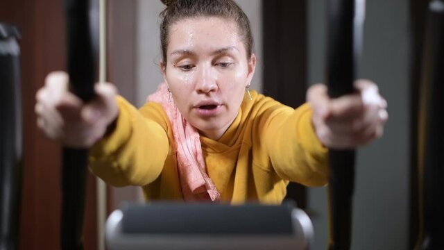 The girl loses strength during training and slides down the sport training machine