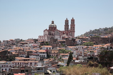 Naklejka premium View of Santa Prisca Church and dense white houses with tile roofs on the hill in Taxco, Mexico 