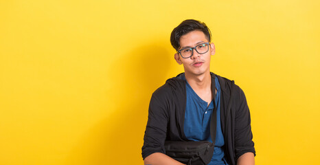 Fototapeta premium Headshot portrait of Asian young handsome man wear eyeglasses or spectacles, studio short isolated on yellow background with copy space, Fashion male beauty concept