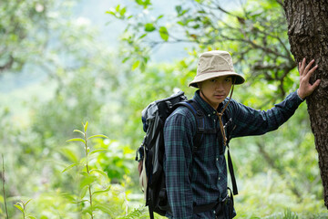 A happy hiking man walks through the forest with a backpack.
