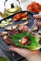 cooked samgyeopsal ( grilled pork belly BBQ ),  wrapping with lettuce, korean cuisine 