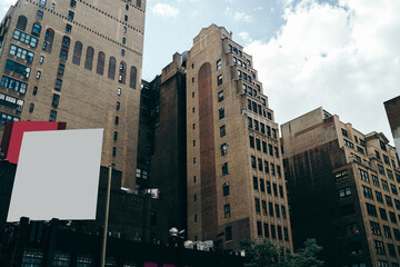 Mock up billboard with blank publicity area for commerce on exterior of high rise building in downtown, tall skyscrapers with apartments for rent and white notice board for advertising information.