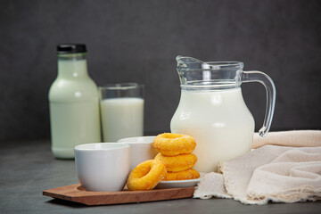 Fresh milk is served with delicious sweets on a black background.