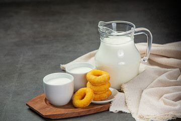 Fresh milk is served with delicious sweets on a black background.