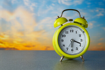 Alarm clock on sunrise background